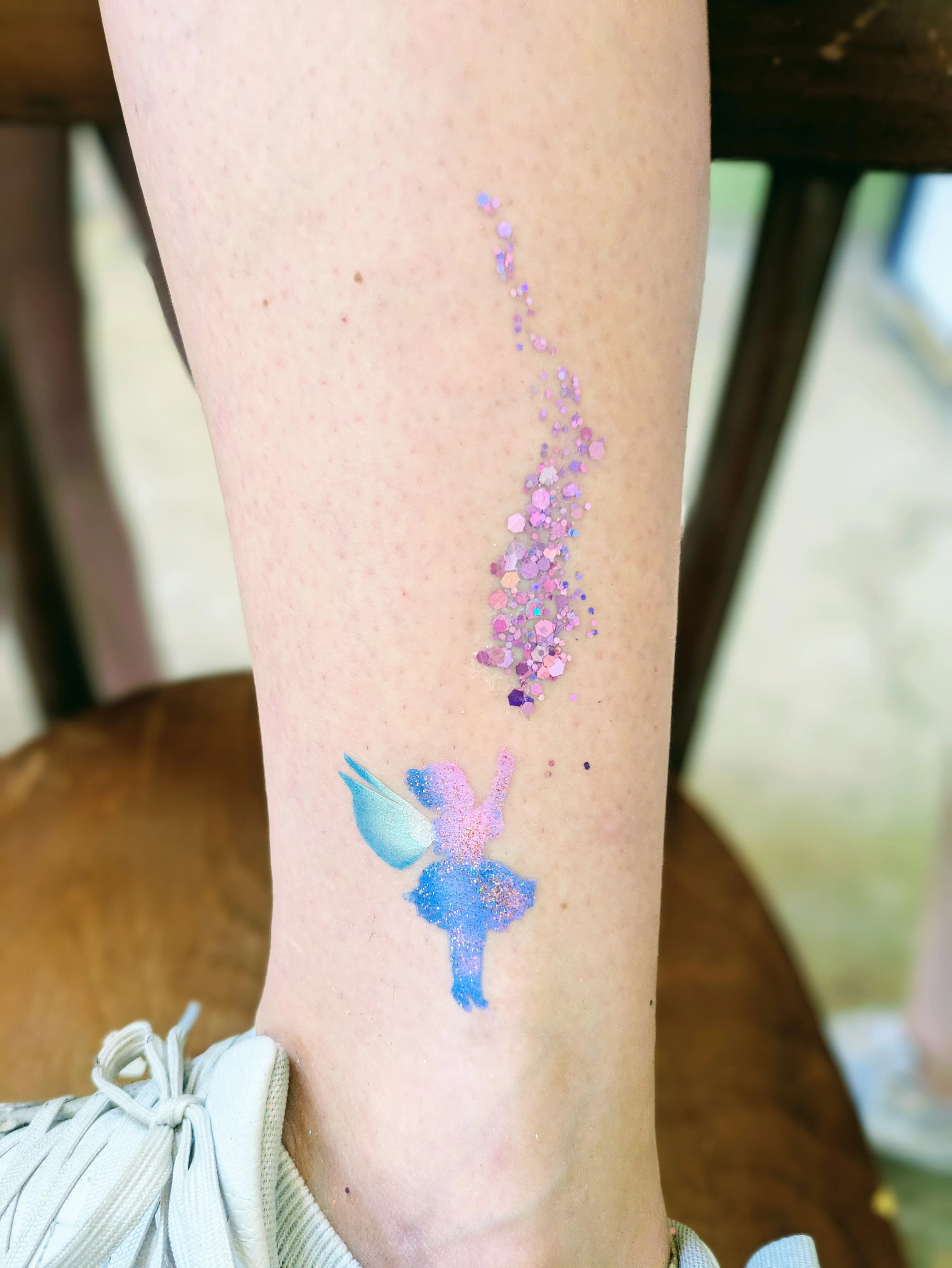 Motif de f&eacute;e bleu et rose accompagn&eacute; d&rsquo;une tra&icirc;n&eacute;e de paillettes violettes et roses